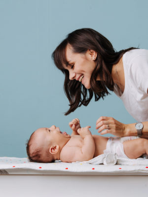 Mother changing diaper on her baby on table