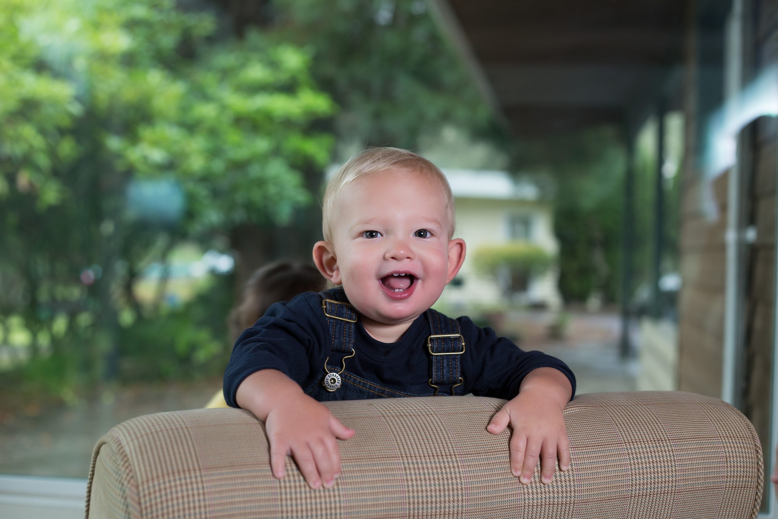 Blond toddler wearing overalls and smiling