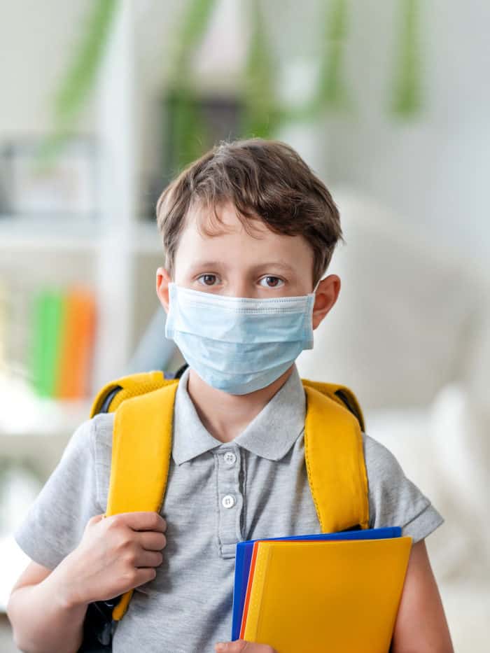 boy wearing backpack and mask going to school