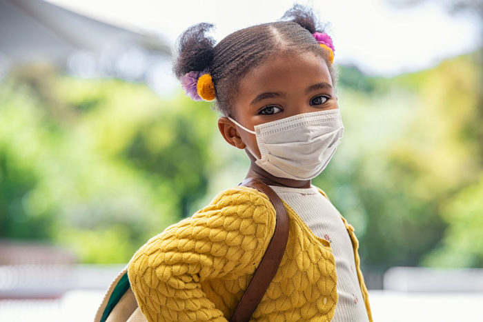 cute little girl with school backpack and protective face mask ready for first day of school