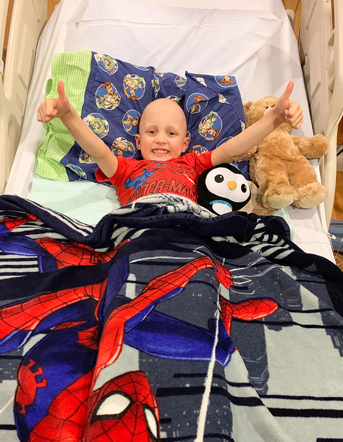 boy in hospital bed smiling and giving thumbs up