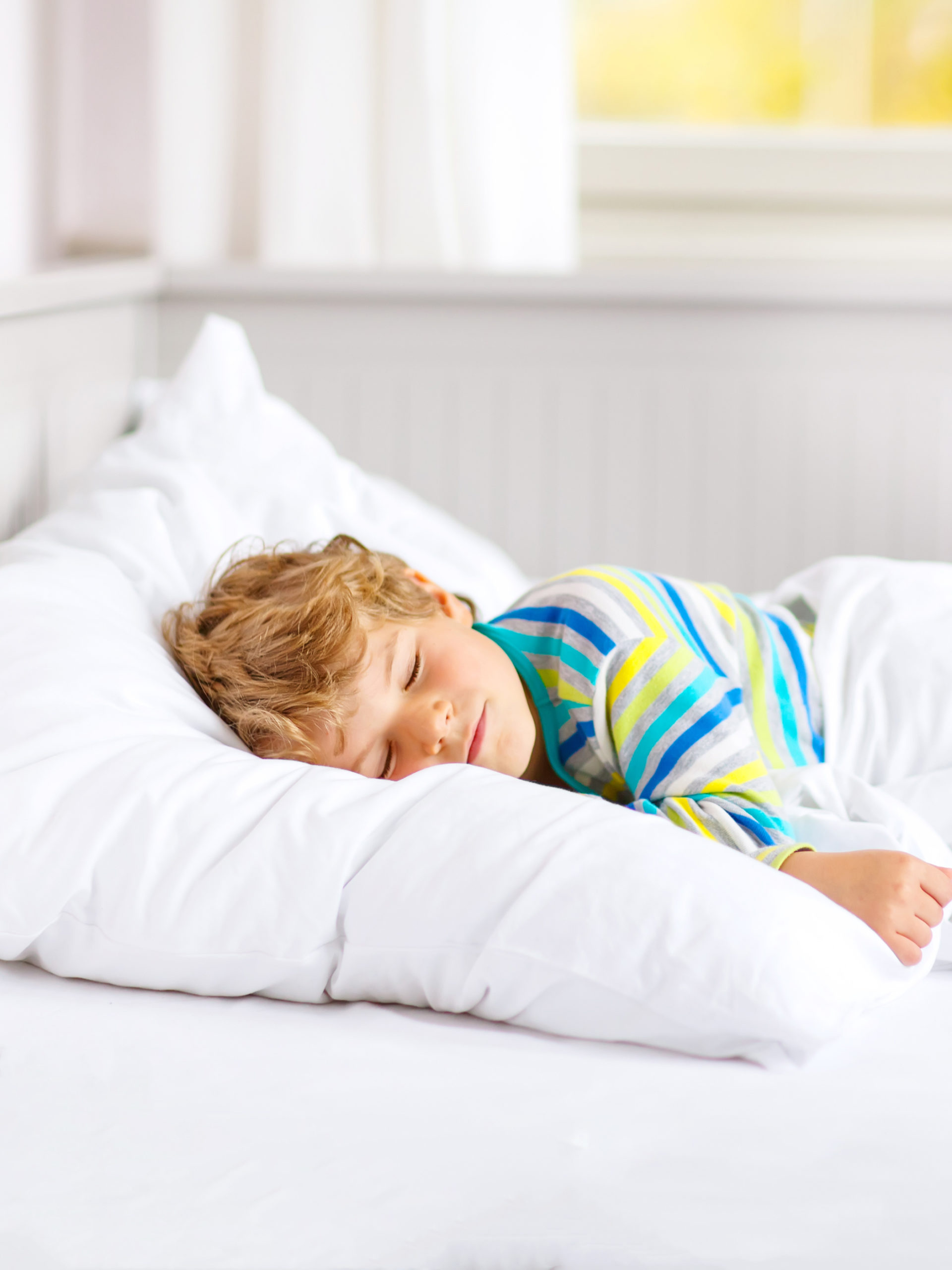 young boy sleeping in bed smiling