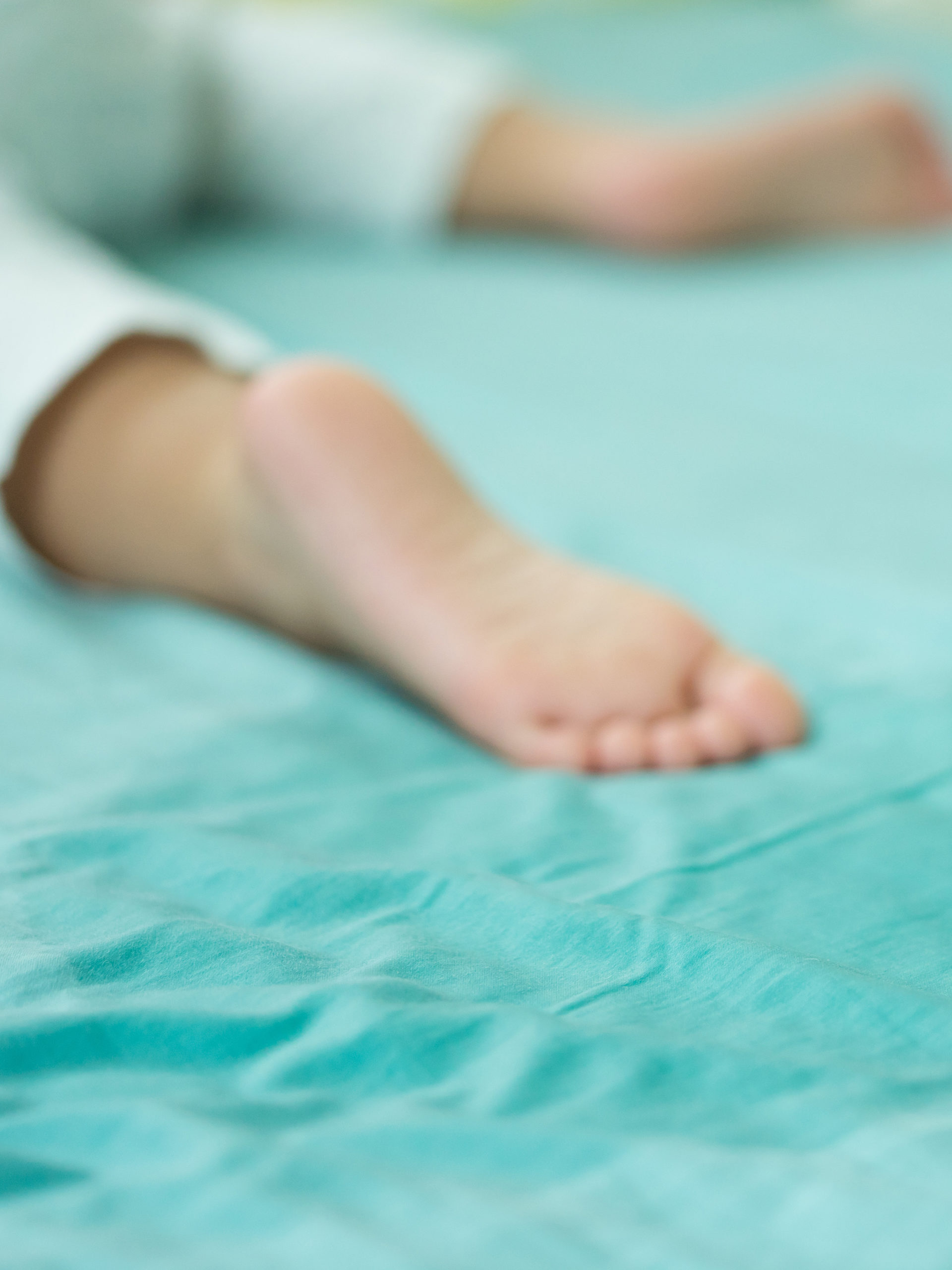 child's foot and wet spot on bed