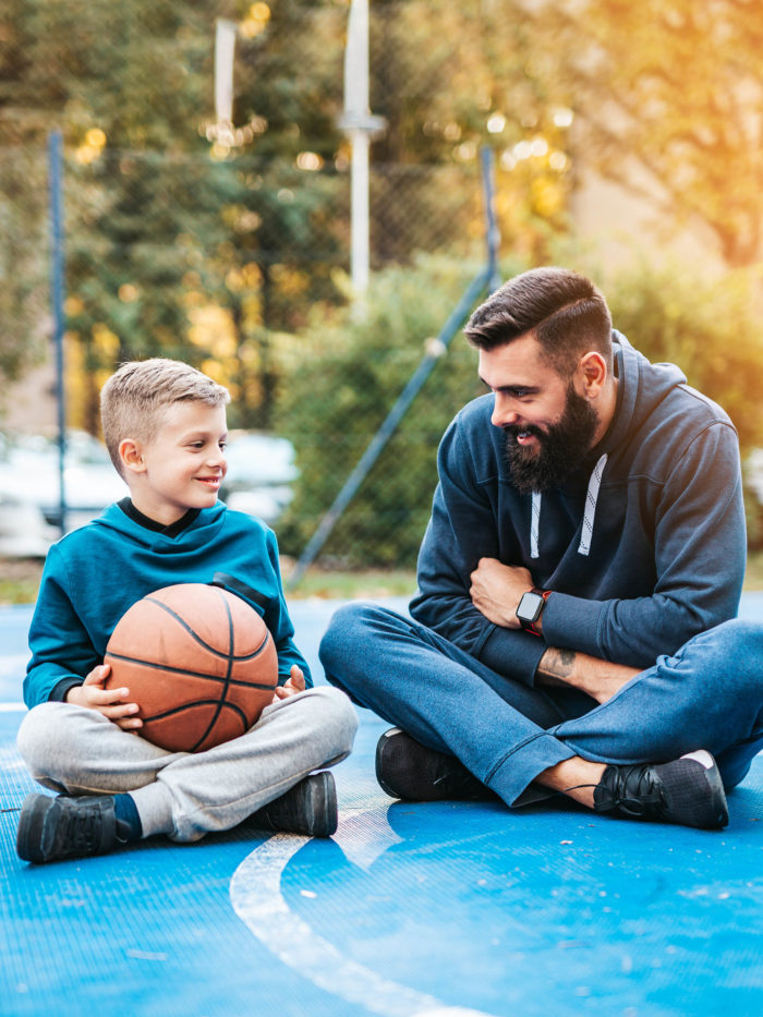 Father and his son enjoying time together on basketball court.