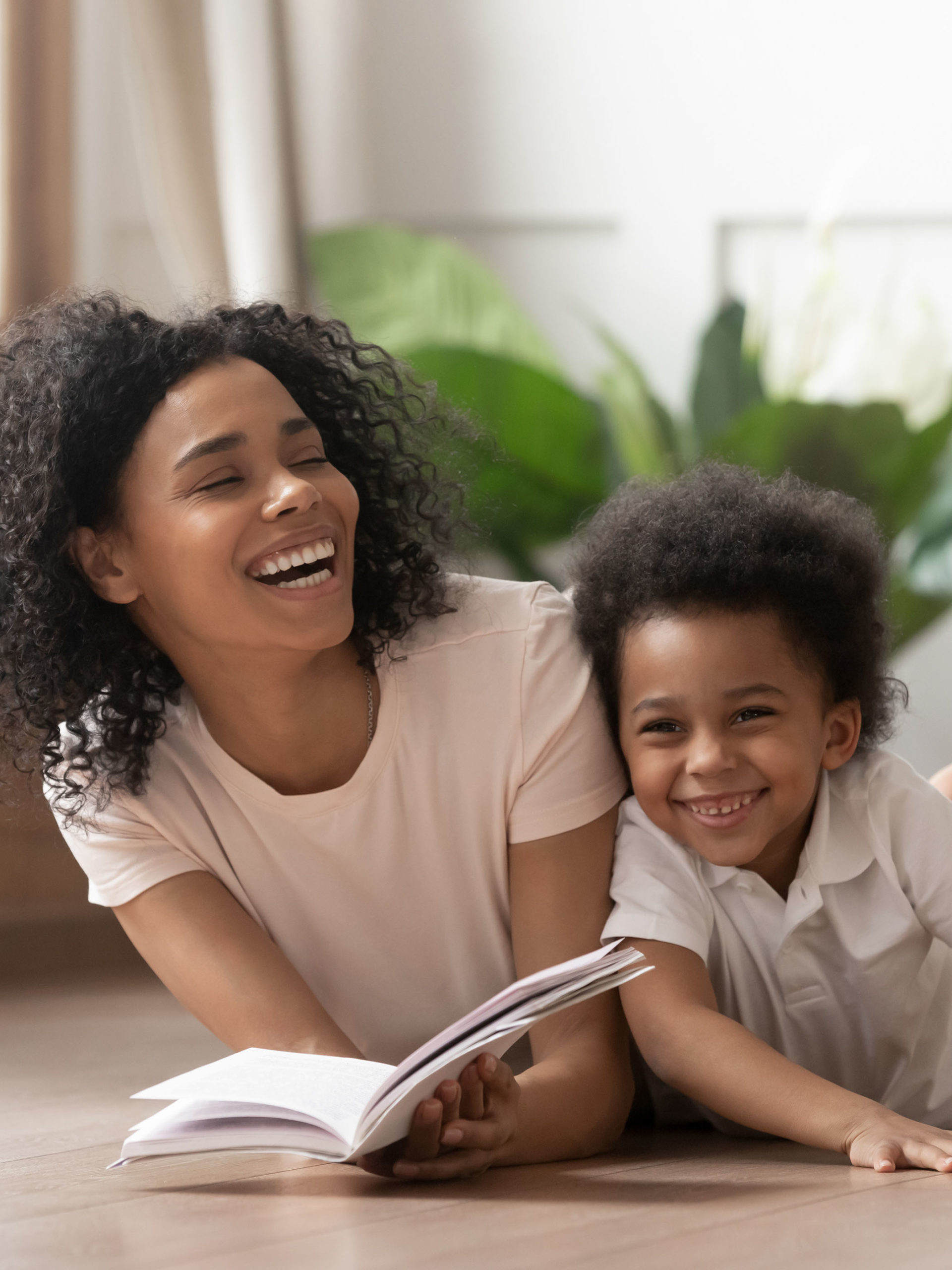 laughing mother with book reading fairy tale story to son