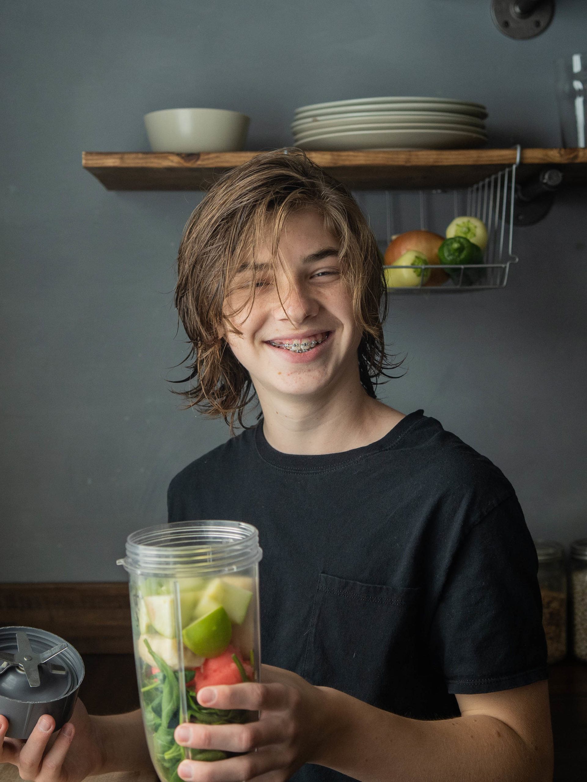 Young teen boy holding smoothy with healthy food and smiling