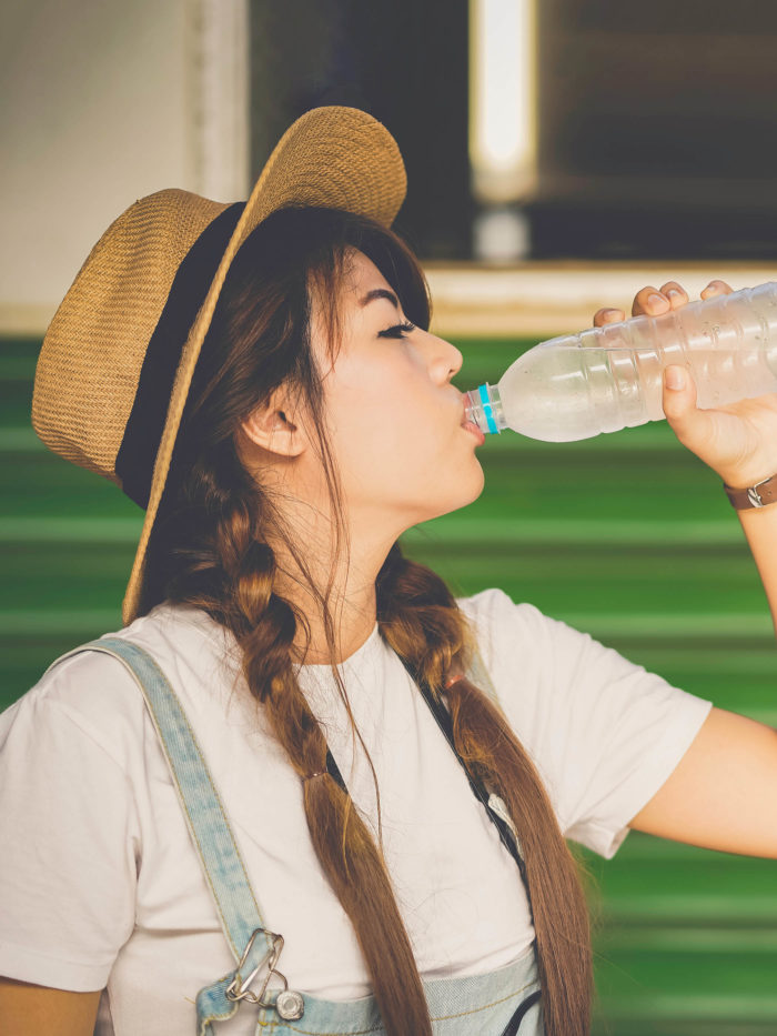 teen girl drinking water from plastic bottle