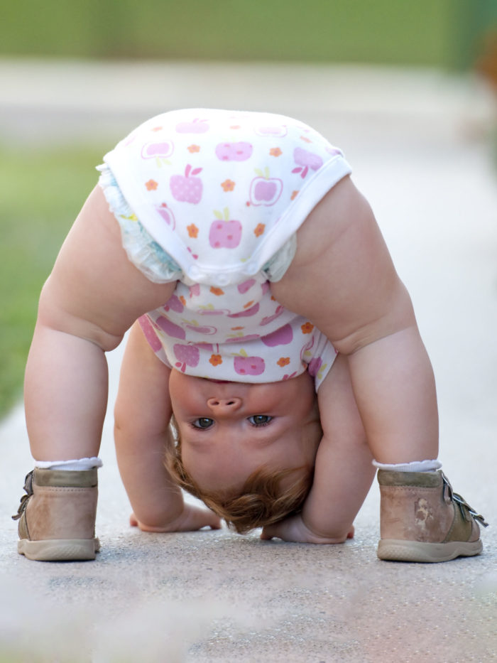 One-year baby girl trying to do a headstand