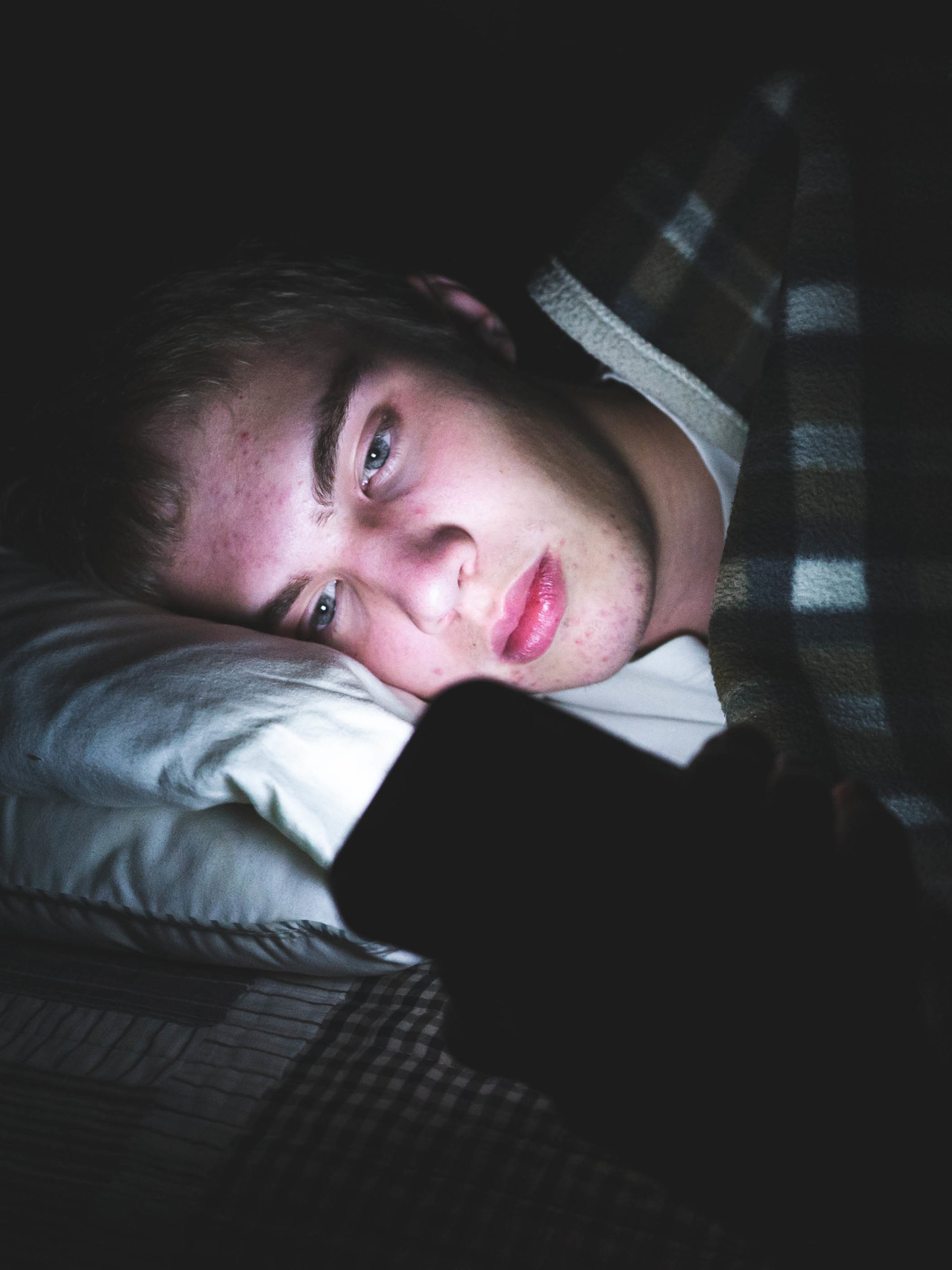 depressed teen boy scrolling through social media late at night