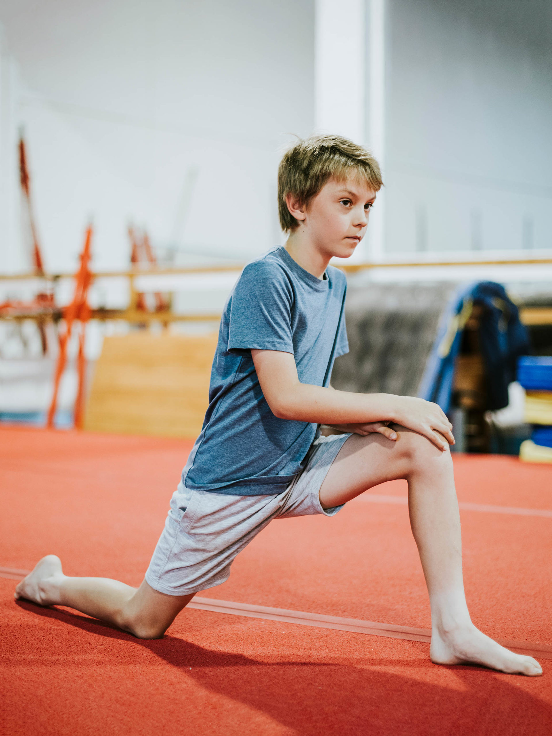 young gymnast in a lunge to stretch his legs