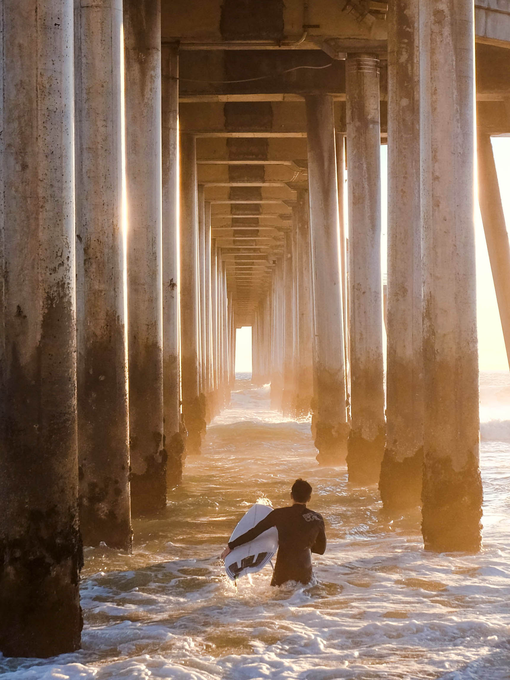 surfer catching sunset waves under the Huntington Beach Pier