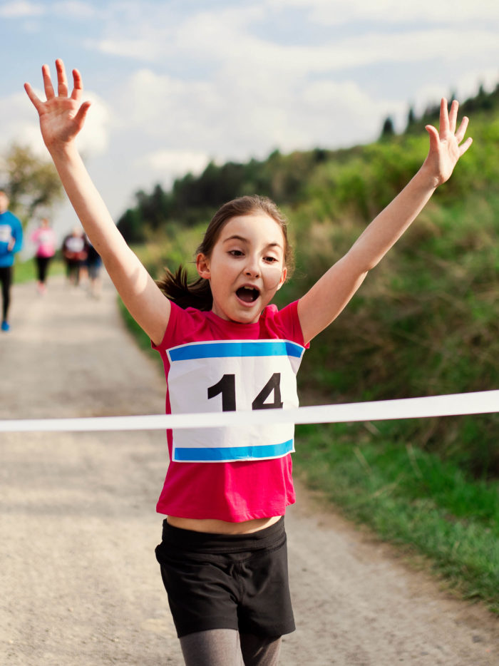 young girl runner crossing finish line in a race