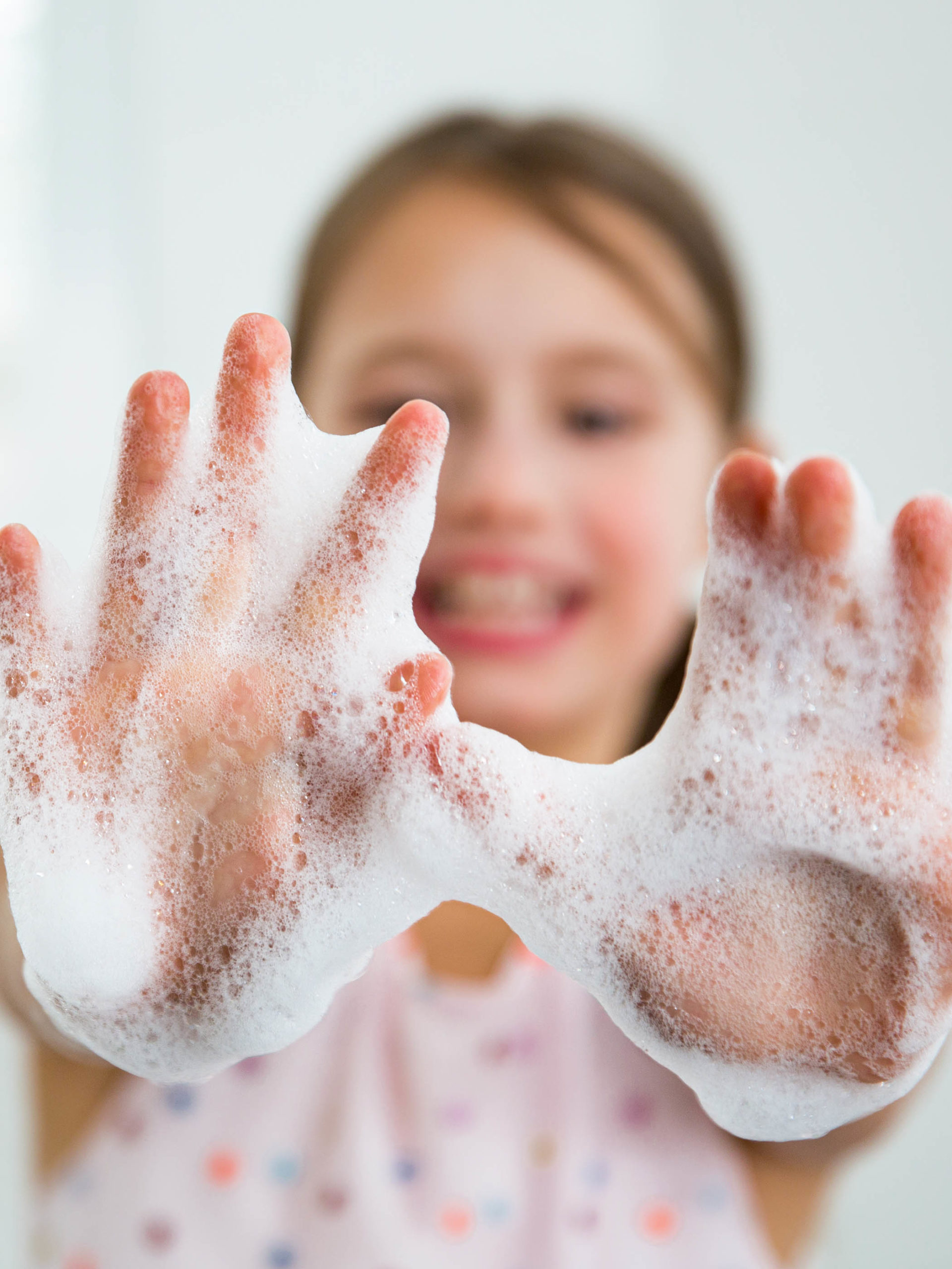 Little girl washing hands with water and soap in bathroom