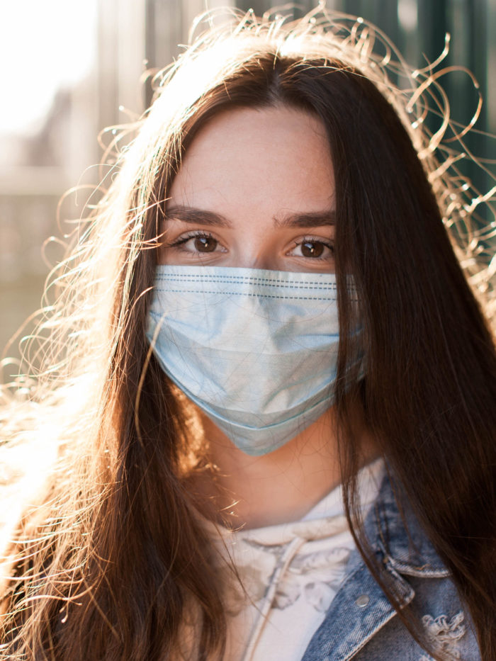 brunette girl in jeans in a protective medical mask
