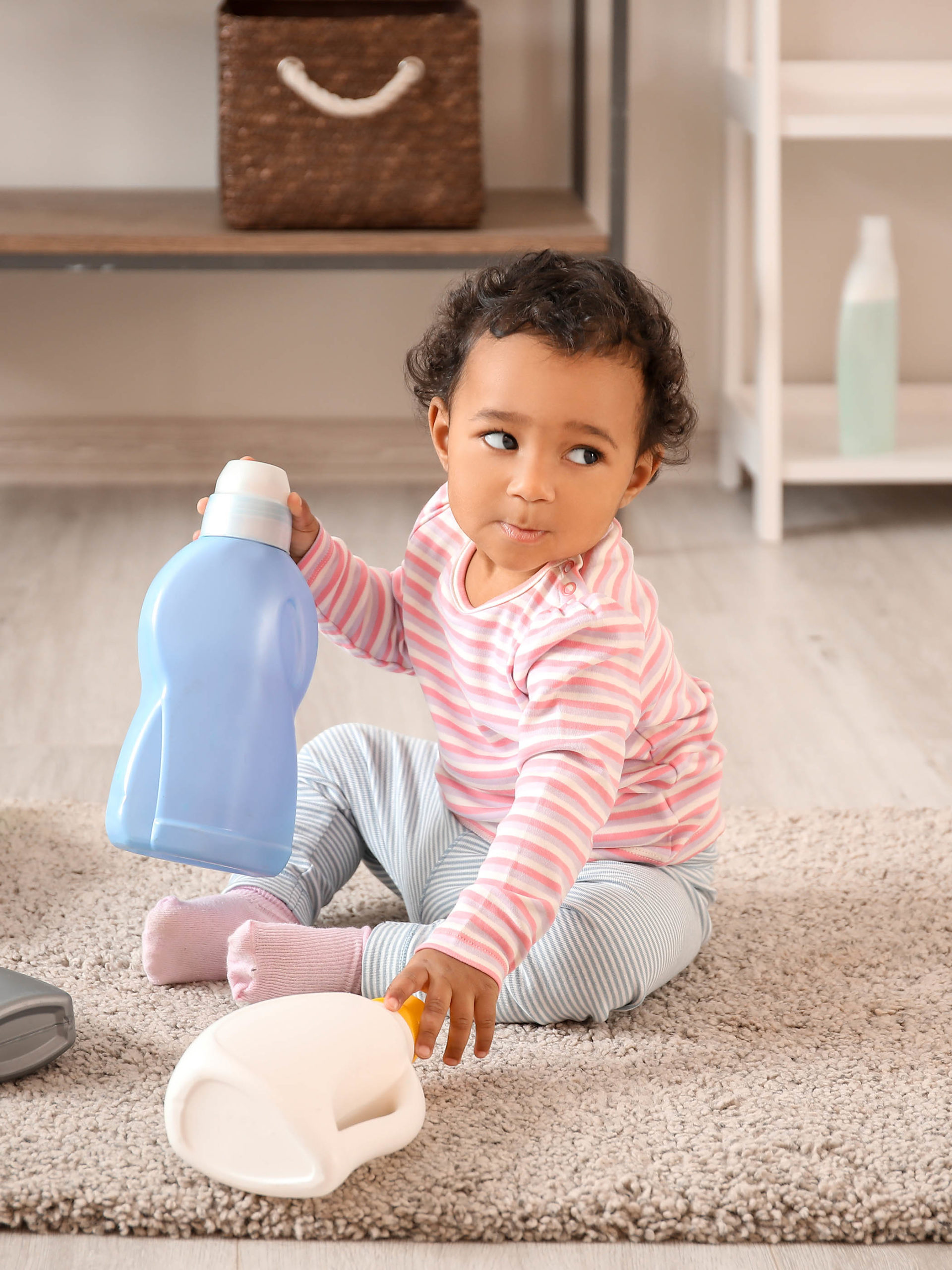 little girl playing with laundry detergent container
