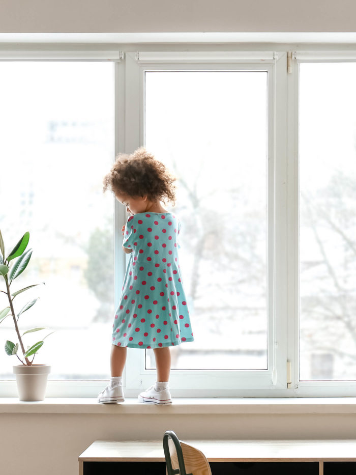 young girl standing near window in danger