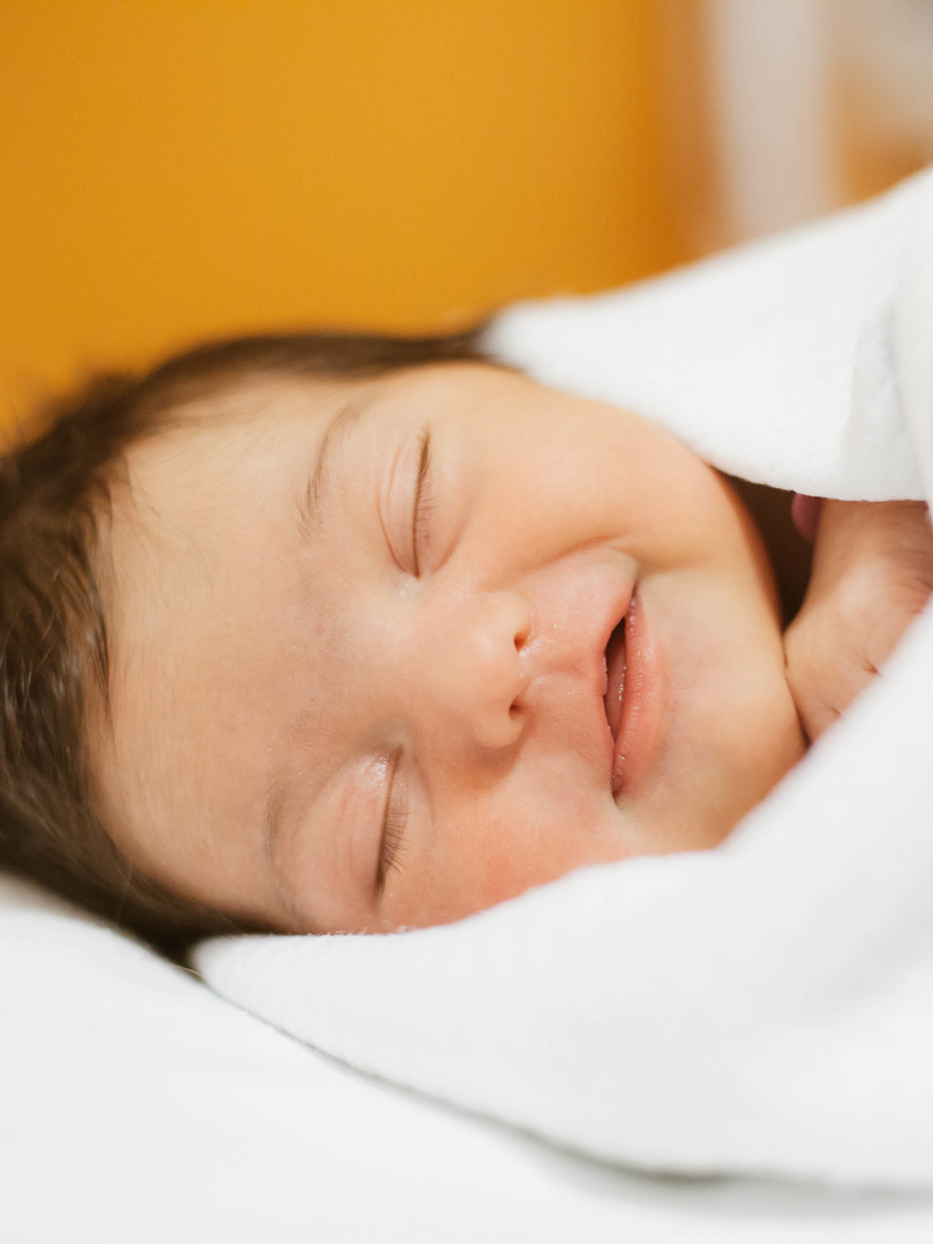 2-day-old newborn baby smiling with eyes closed