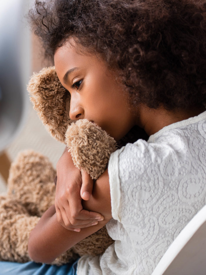 girl with anxiety hugging teddy bear during therapy session