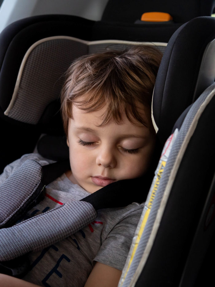 toddler boy sleeping in his car booster seat