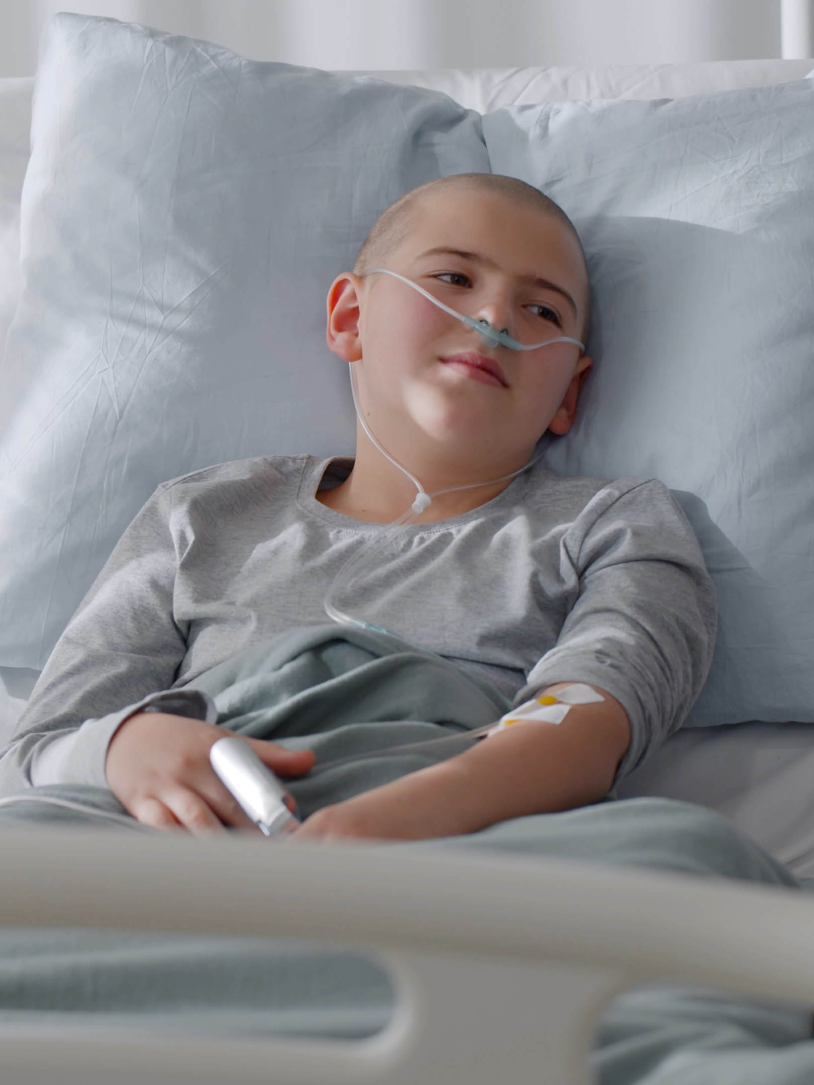 bald teen boy cancer patient lying in hospital ward