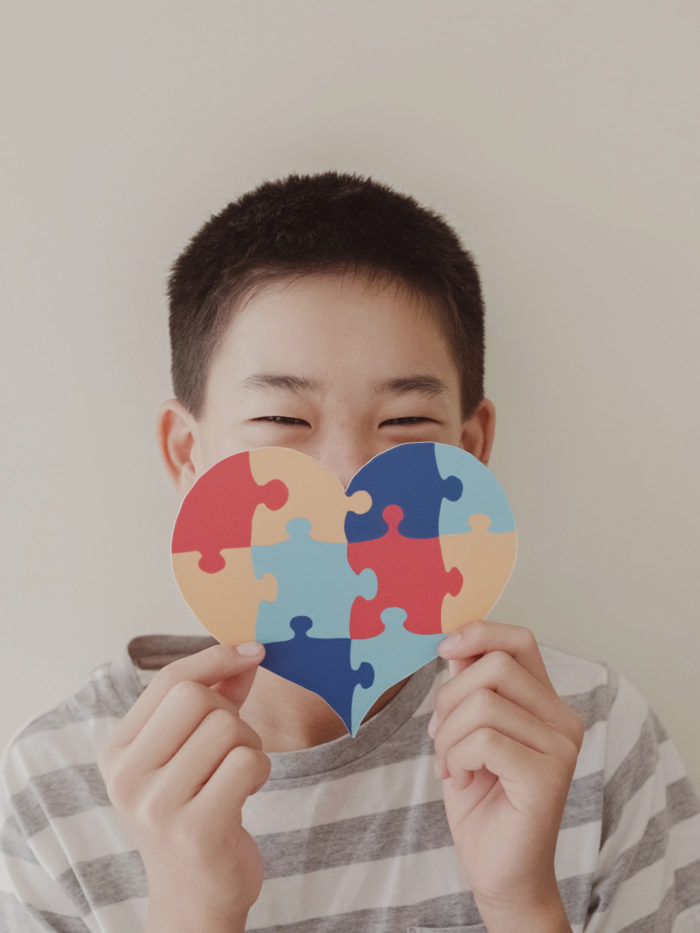 Preteen boy holding large heart-shaped jigsaw puzzle