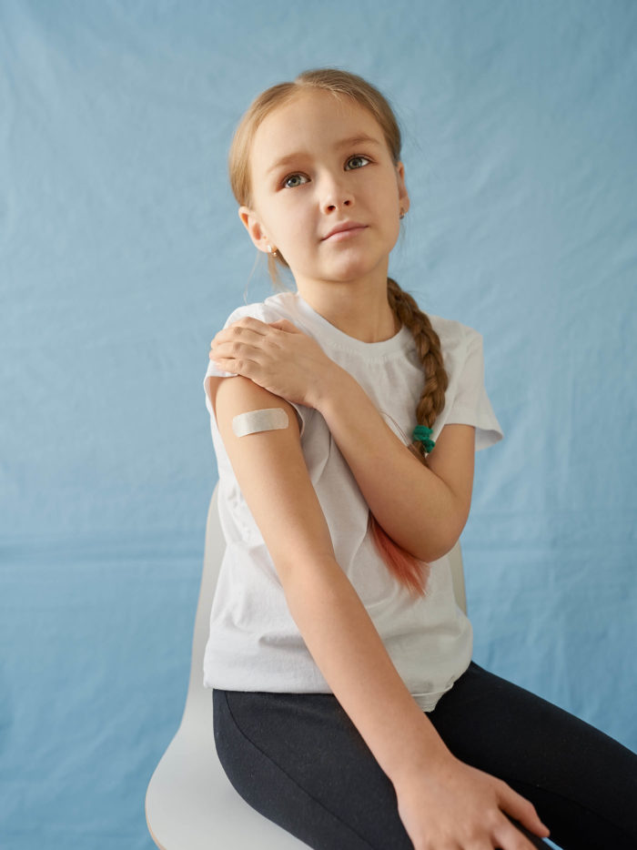 tween girl with bandage on her arm because she received a vaccine