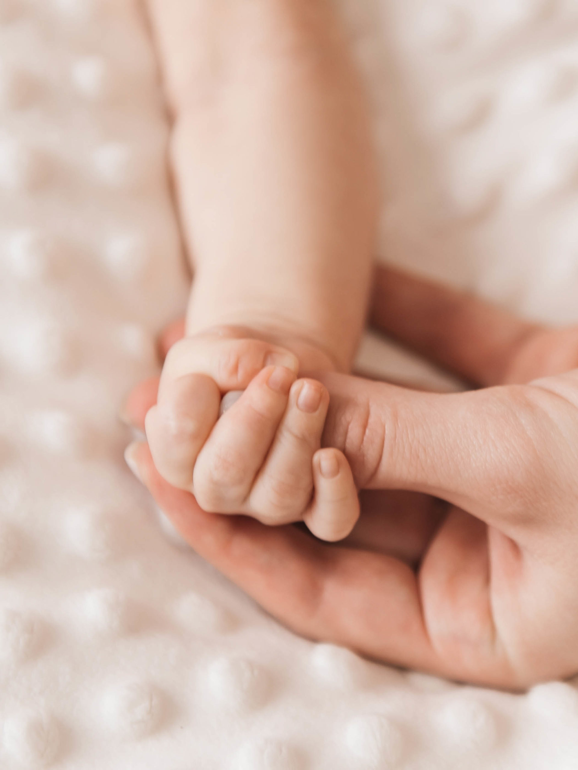 closeup of a mother holding tiny baby hand in hers