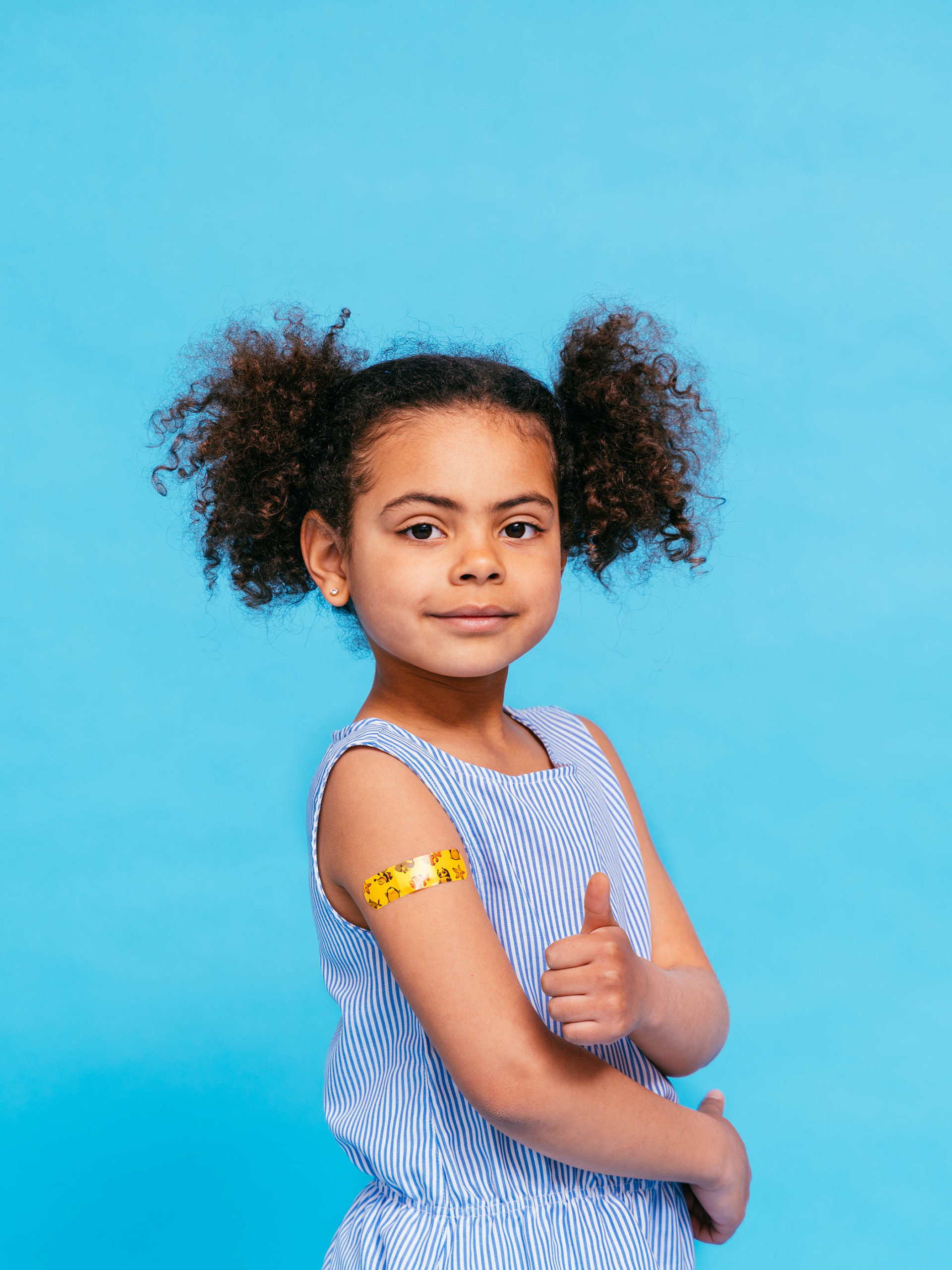 little girl who has just received vaccine giving a thumbs up