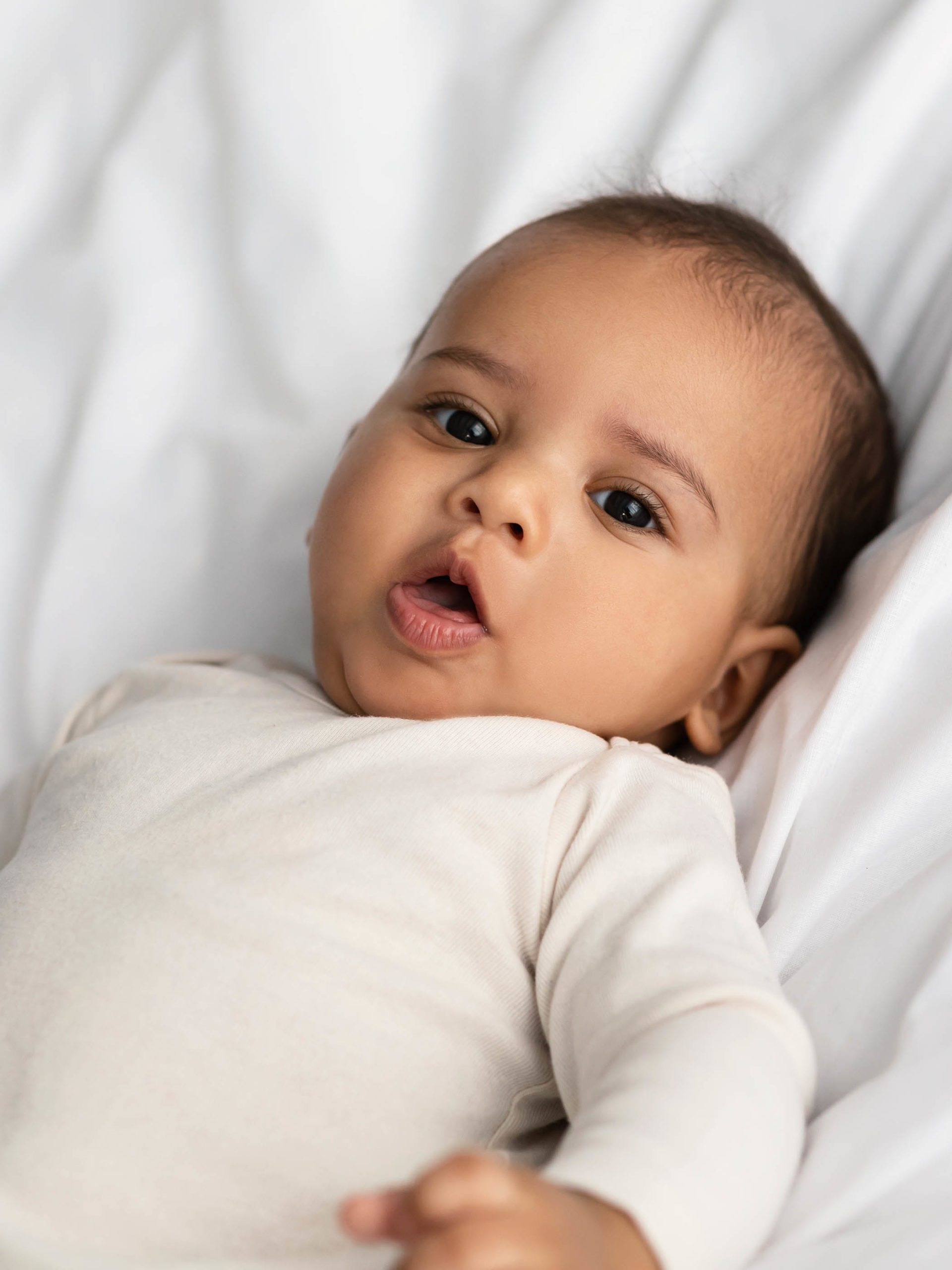 adorable infant lying in bed coughing