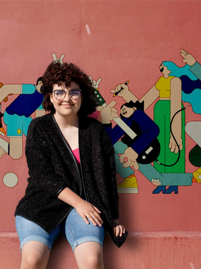 overweight teen girl sitting in front of a mural