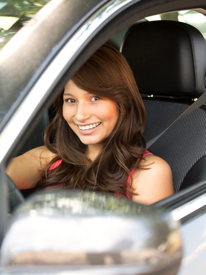smiling teen girl in the drivers seat of a car