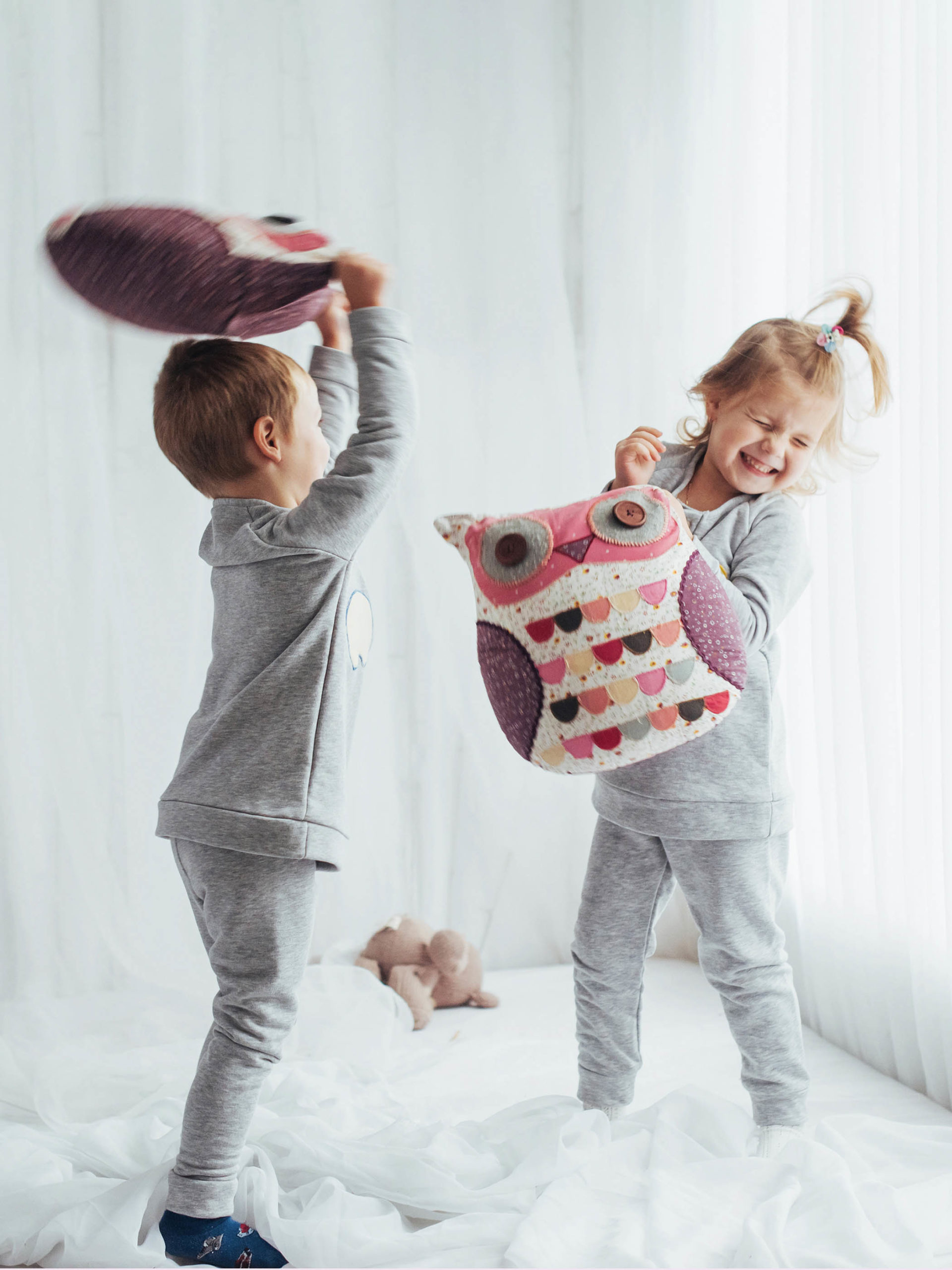 siblings jumping on the bed and havng a pillow fight