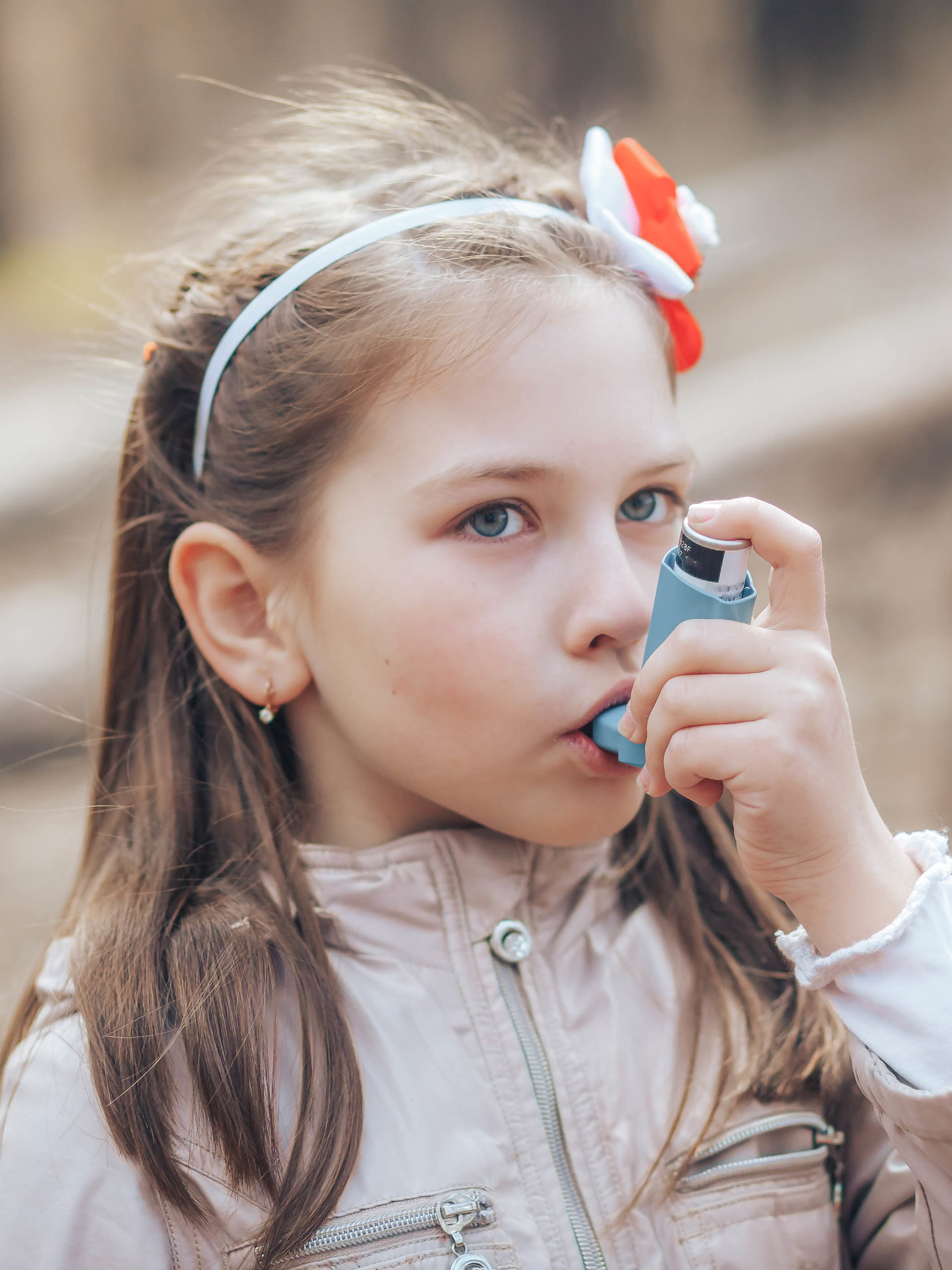 Girl having asthma attack using her asthma inhaler