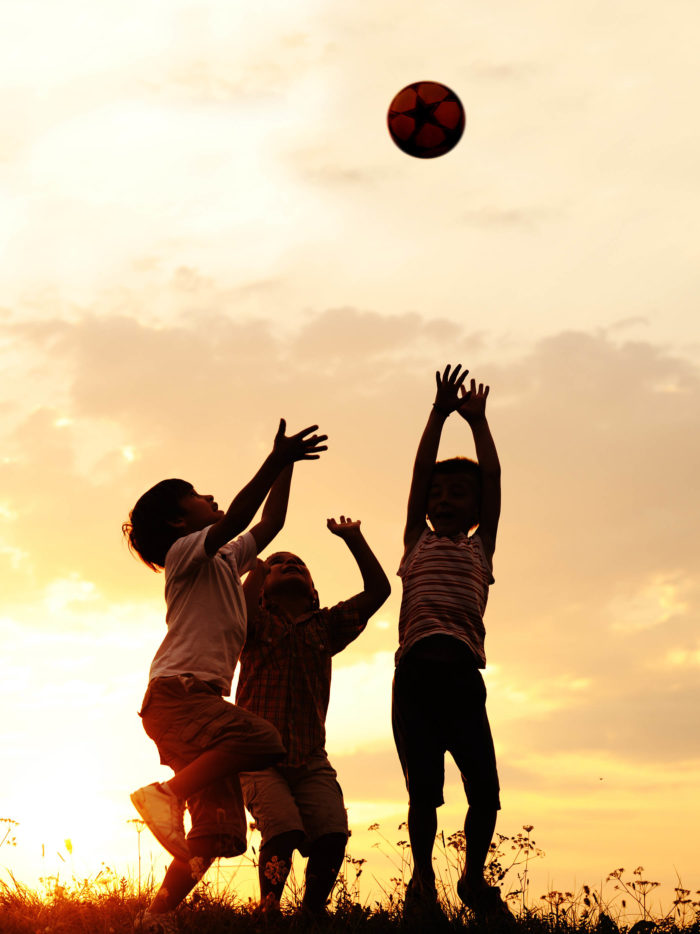 silhouette of children playing at sunset with a ball