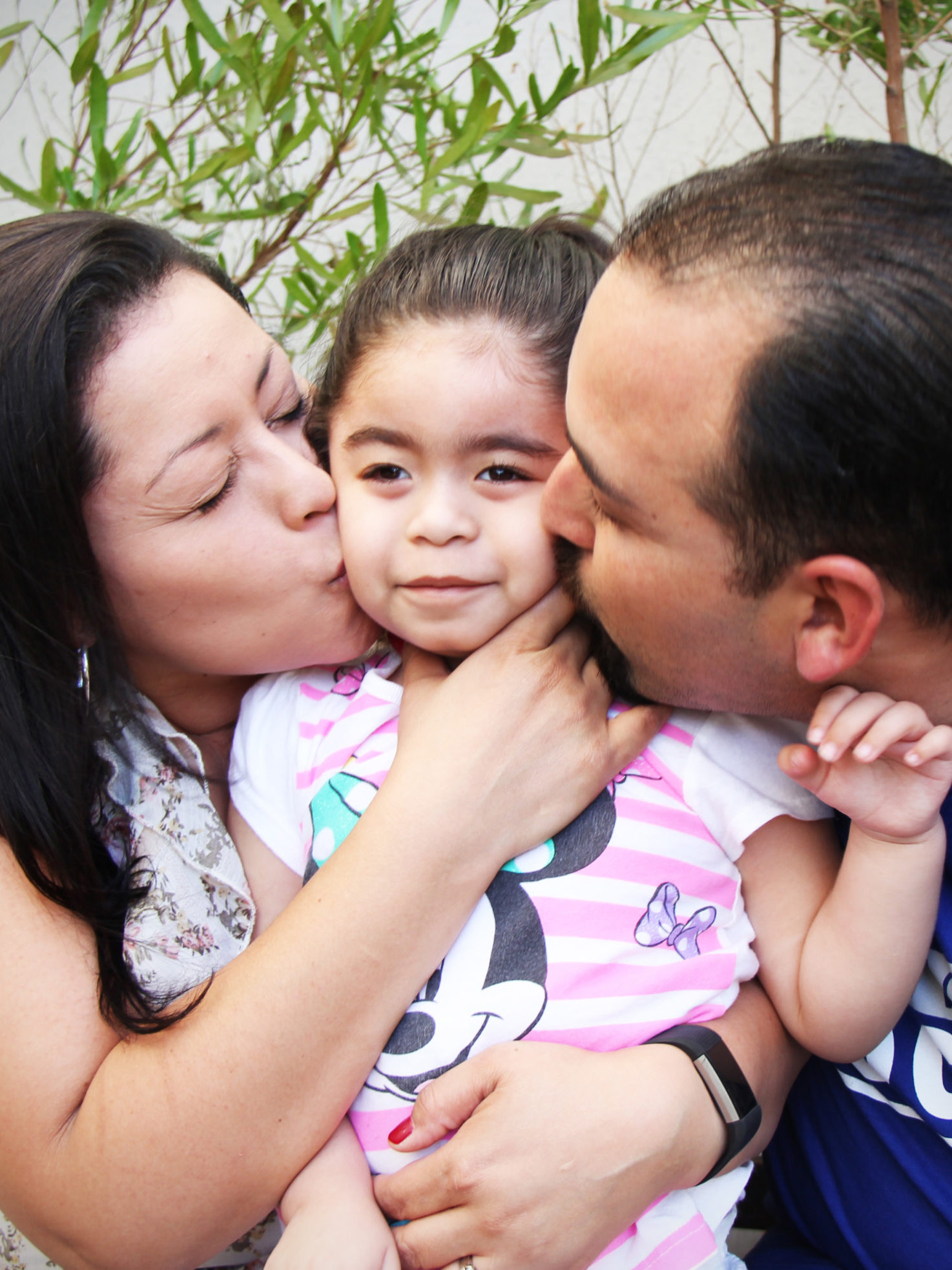 Gladys Salazar and Paul Gomez kissing ther daughter on the cheek