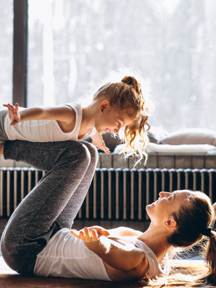 mother and daughter doing partnered yoga together at home