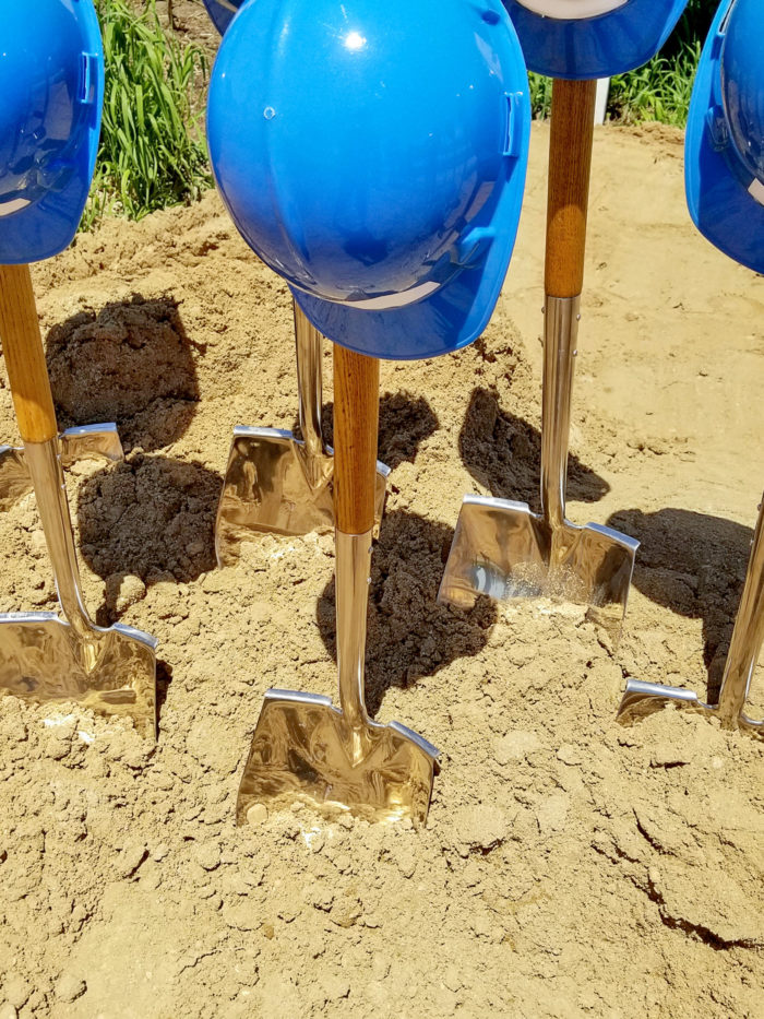 blue hard hats and shovels in the dirt for ceremonial ground breaking