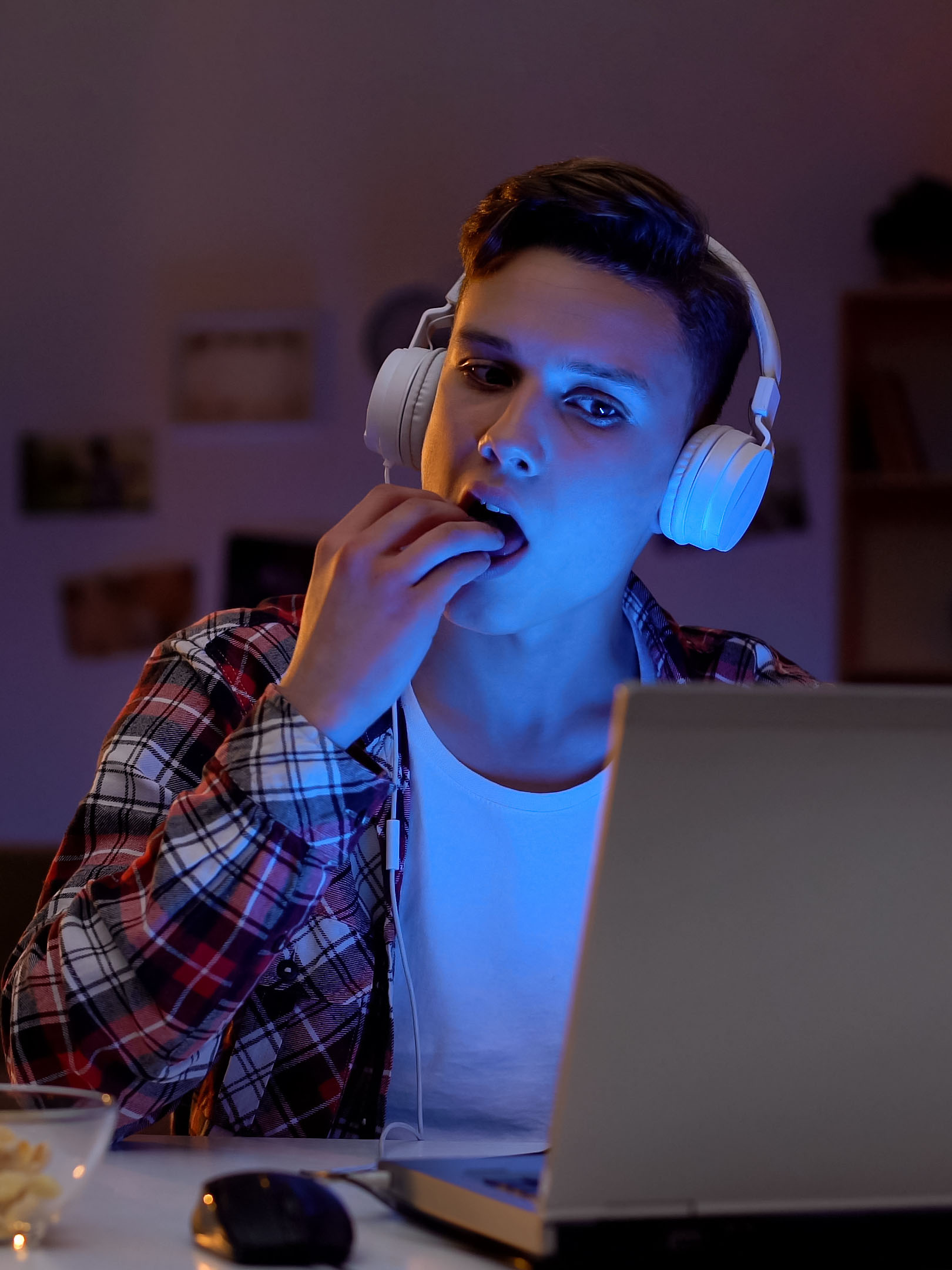 Teenage boy playing computer game and eating snack