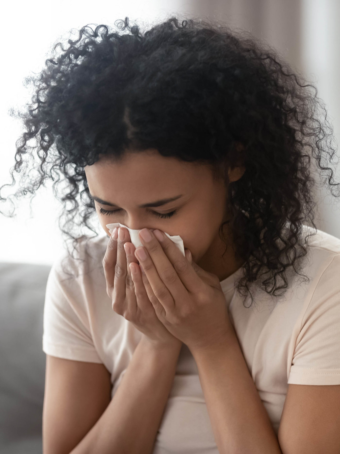 young woman with allergies blowing her nose