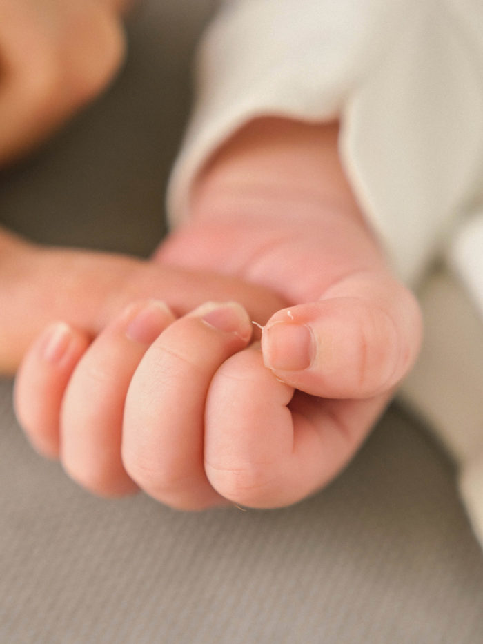 close up of tiny baby hand clutching parent's finger