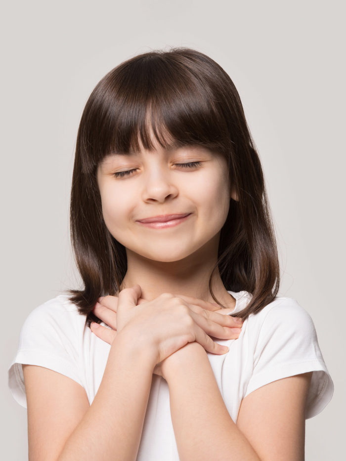 girl holding her hands at heart feeling grateful, smiling