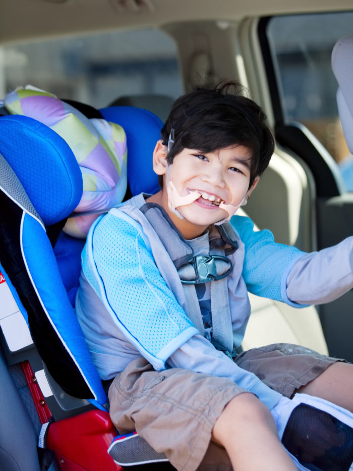 disabled six year old boy smiling in car seat