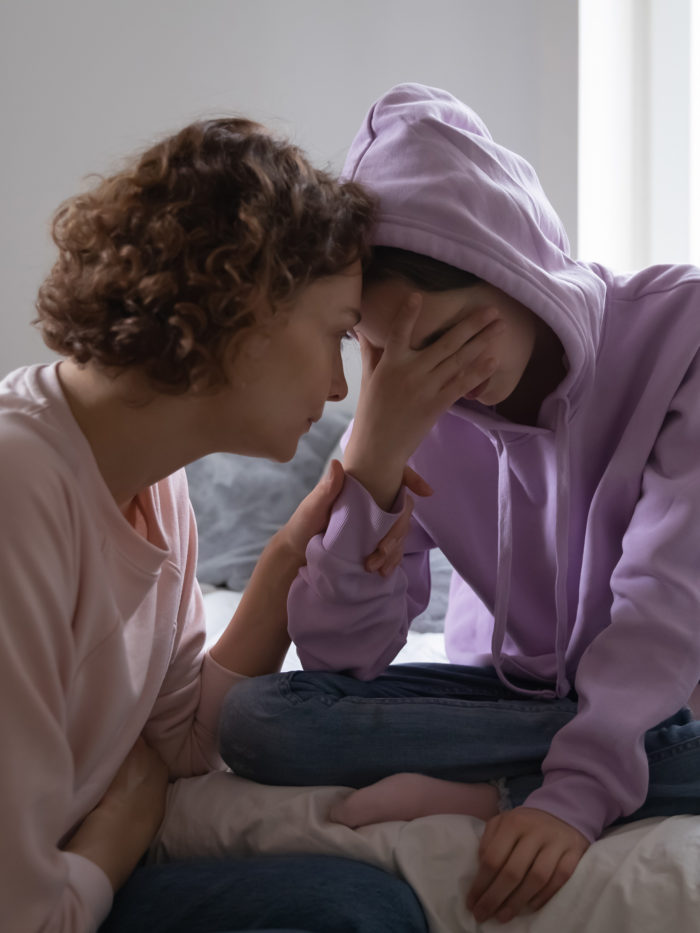 Worried parent young mom comforting depressed crying teen daughter