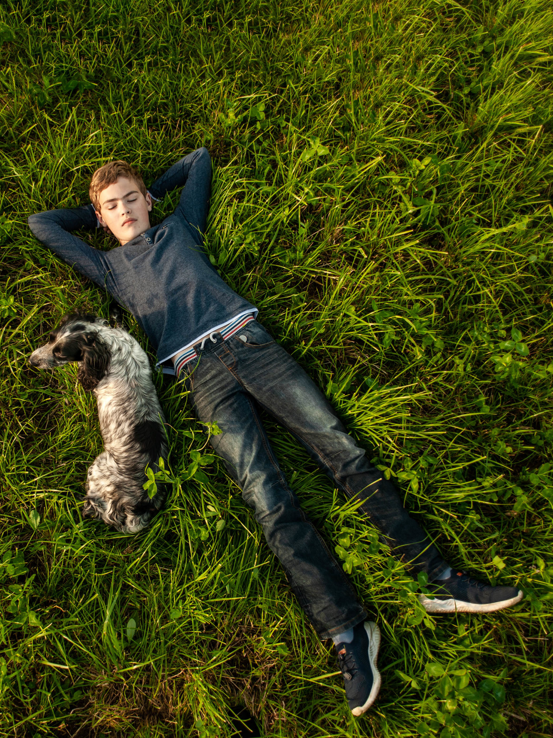 teen boy lies in the grass with his beloved pet dog