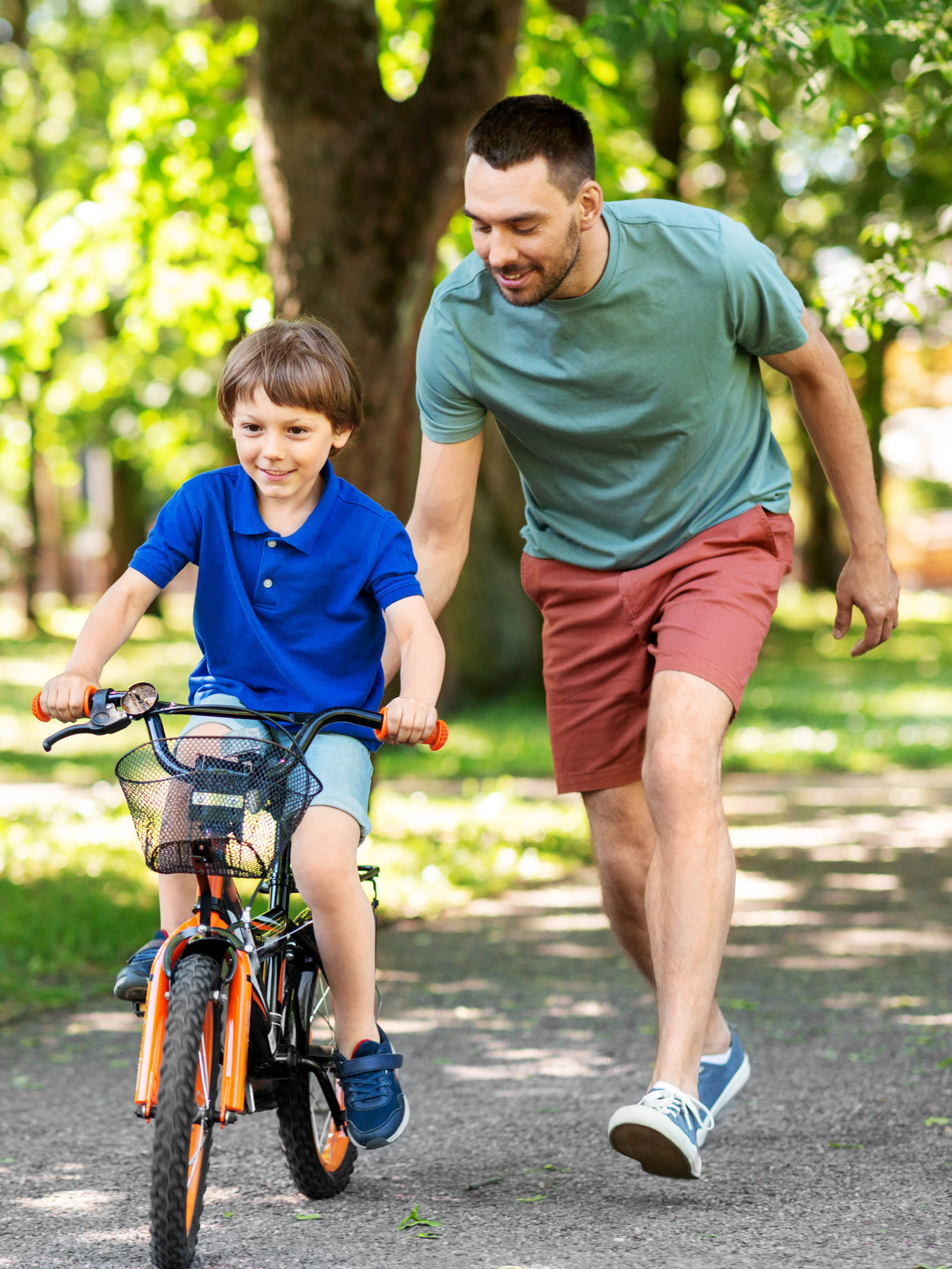 happy father teaching little son to ride bicycle at park