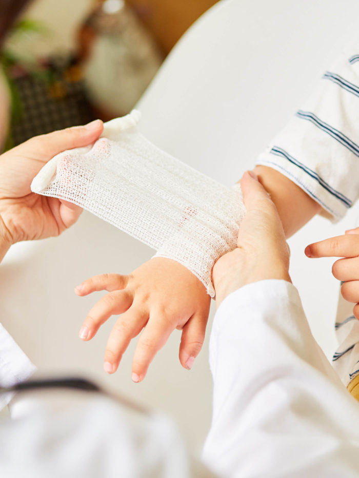 Pediatrician wraps bandage around child's wrist after an injury