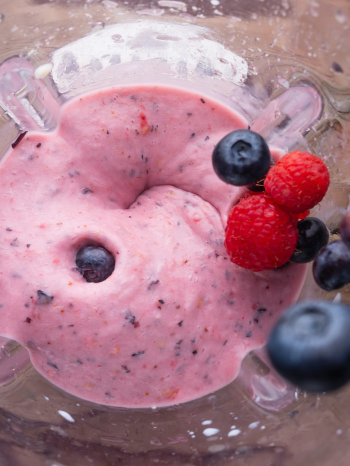 blender top view with healthy pink smoothie with raspberries and blueberries