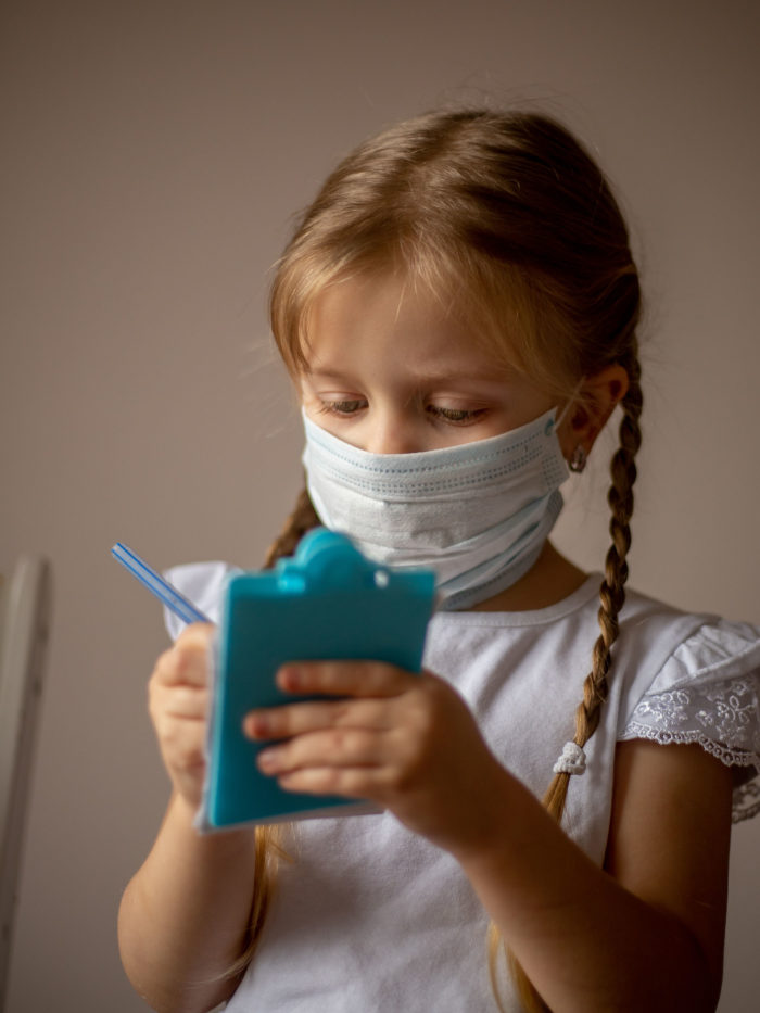 A little girl pretends to write a prescription for a patient