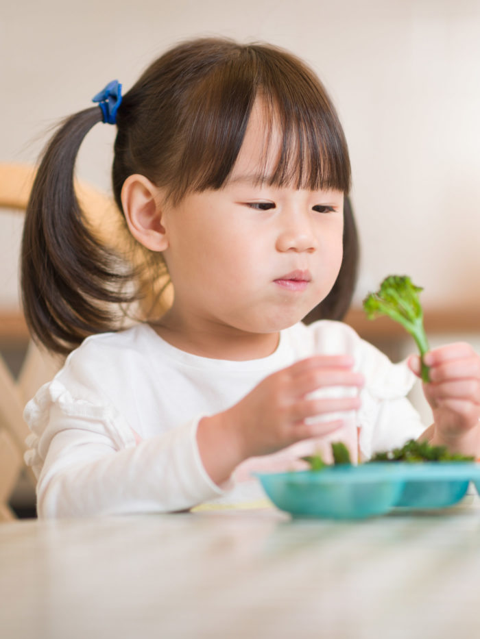 young girl eating fresh green vegetables