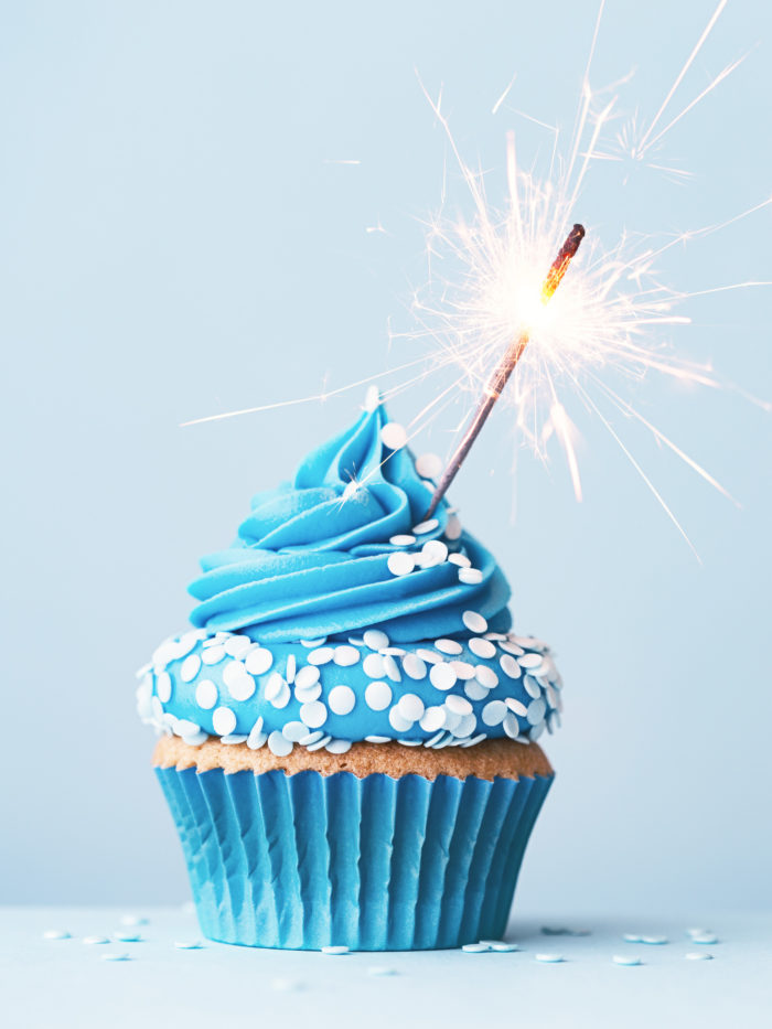 blue birthday cupcake with celebration sparkler and sprinkles